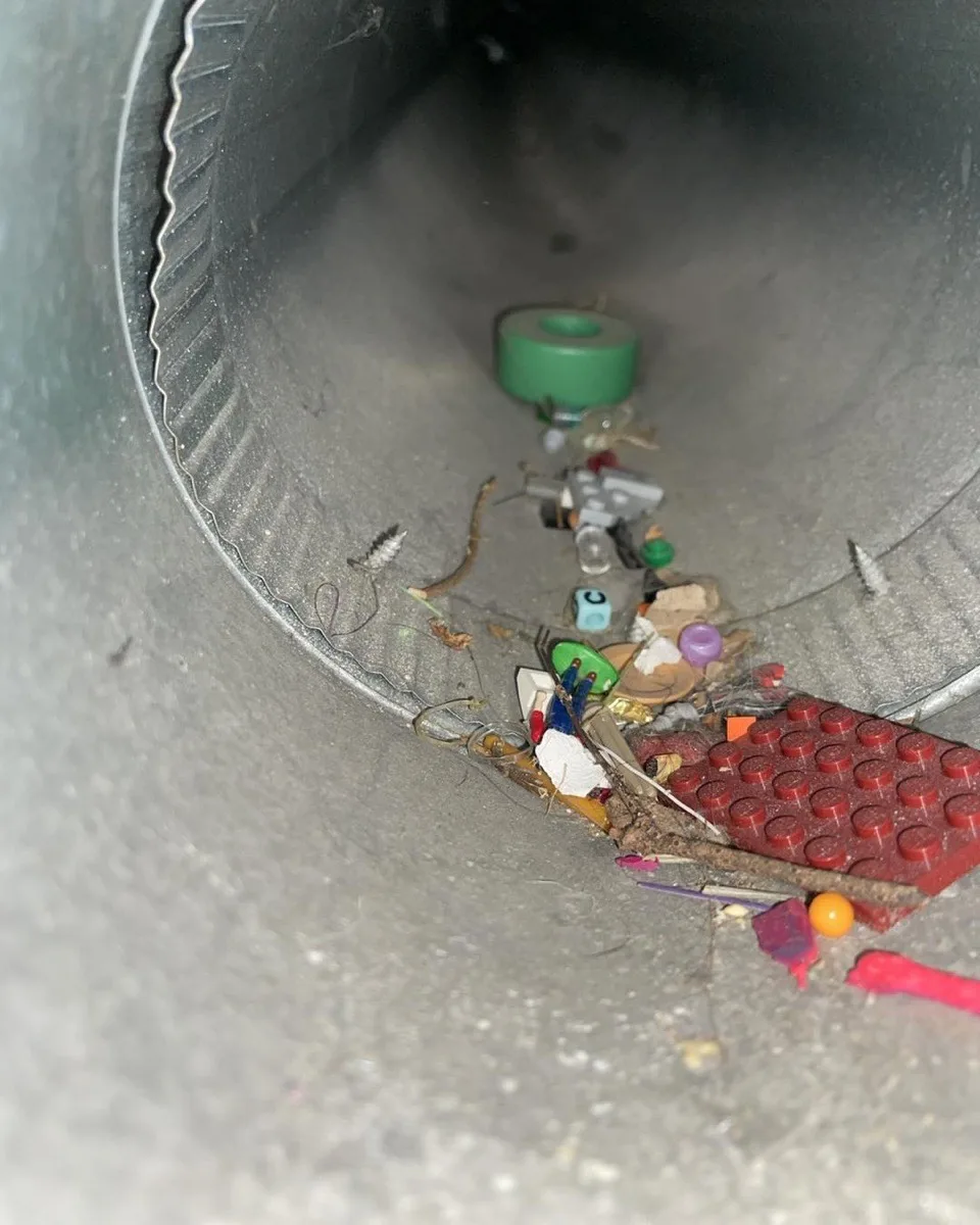 A kid's treasure chest — LEGO bricks, toy figures, and marbles found inside a residential duct