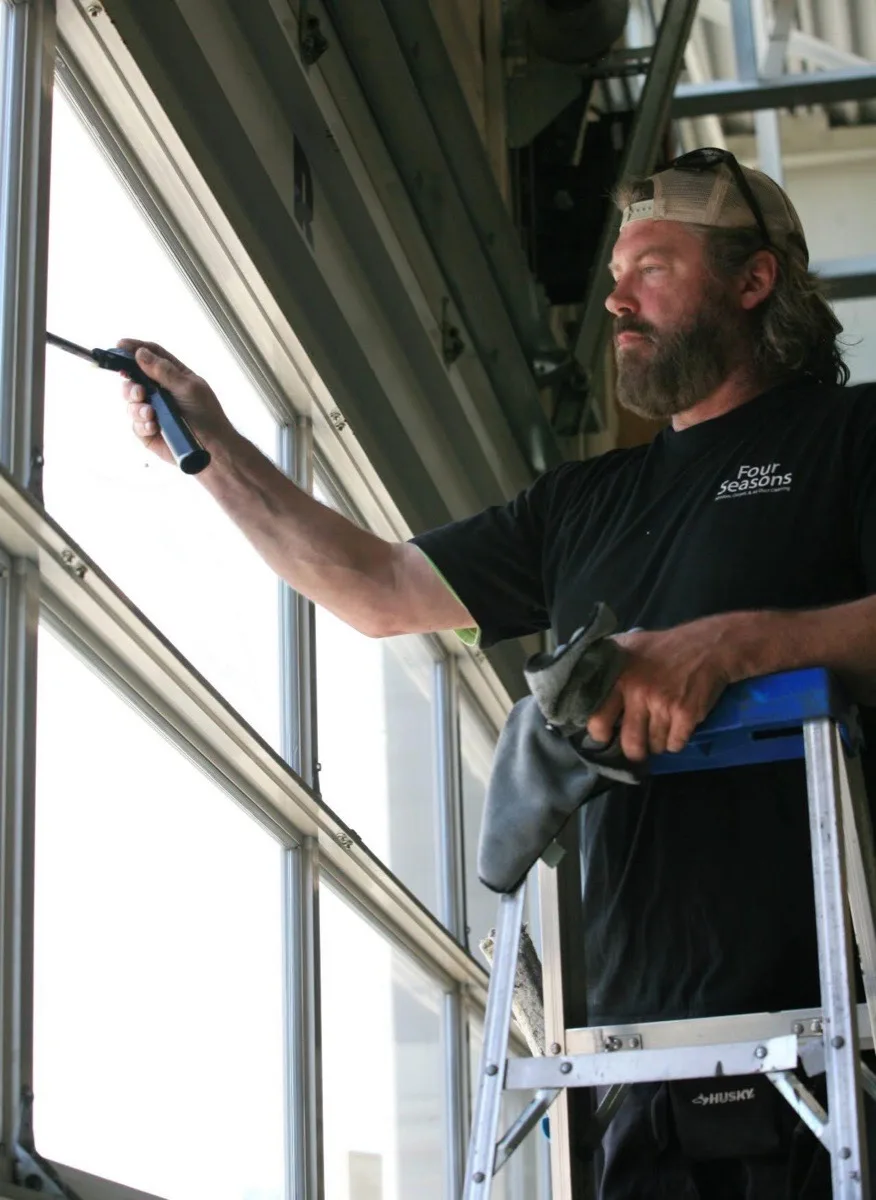 Matt Bertsch on ladder cleaning commercial windows in his Four Seasons shirt