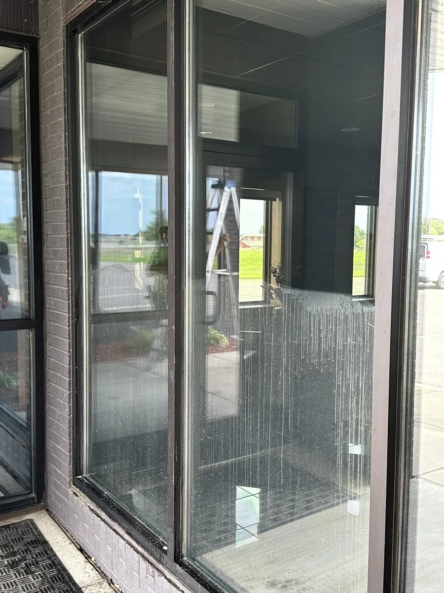 Commercial storefront windows with hard water streaking and mineral deposits — before cleaning