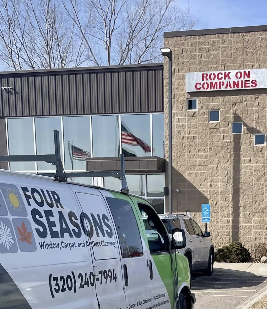 Four Seasons van and equipment trailer parked at a commercial building