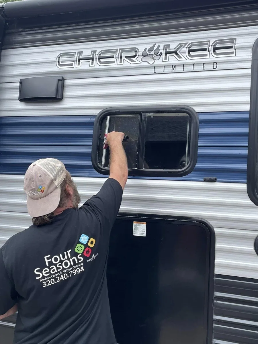 Four Seasons technician cleaning a window on a residential property