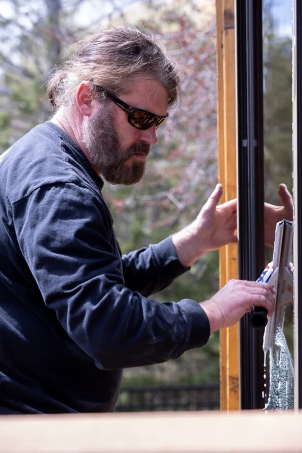 Close-up of Matt Bertsch working a squeegee on an exterior window frame