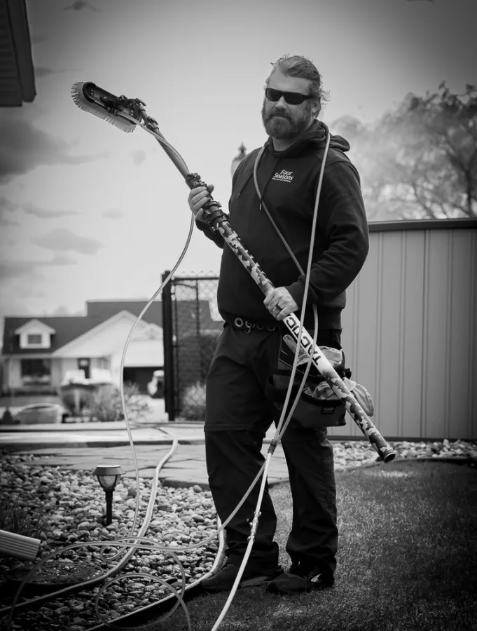 Matt Bertsch holding a water-fed pole window cleaning system — black and white portrait
